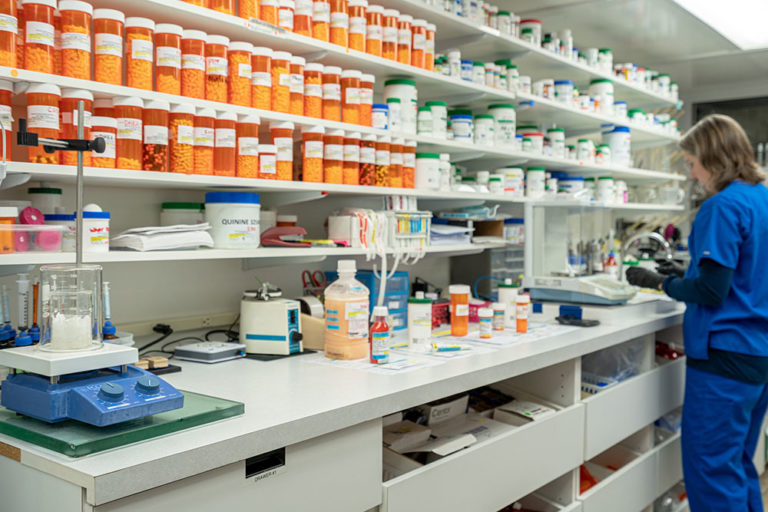 Drug Compounding, Image of one of our pharmacists working behind the counter on a customers prescription.