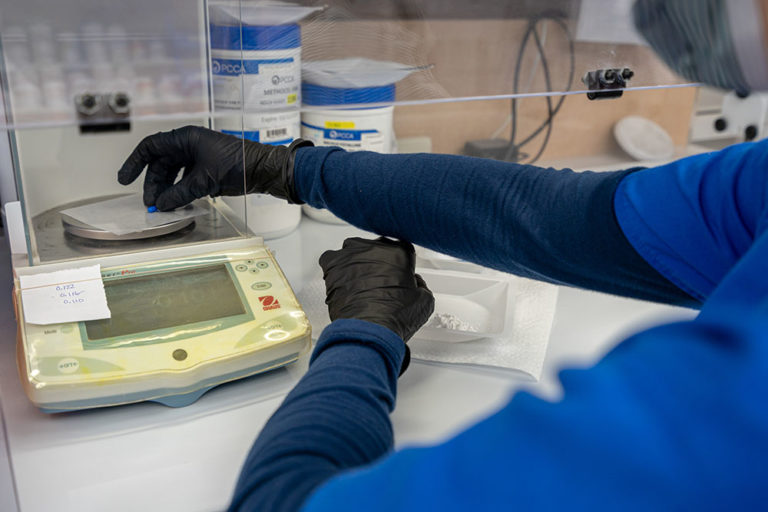Compounding Drug Store, Image of one of our pharmacists weighing a drug compound capsule.